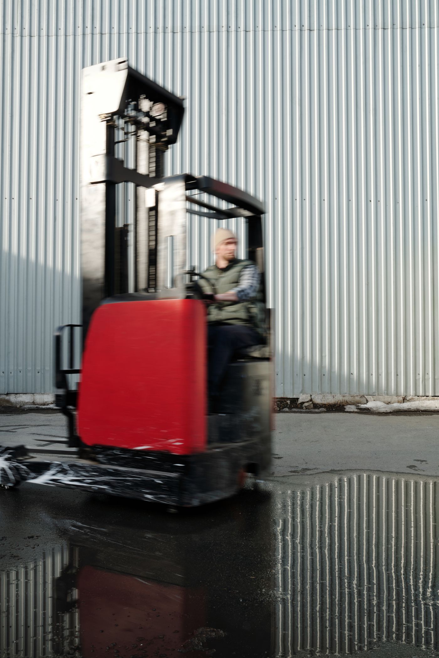 Forklift operator moving through an outdoor warehouse work area