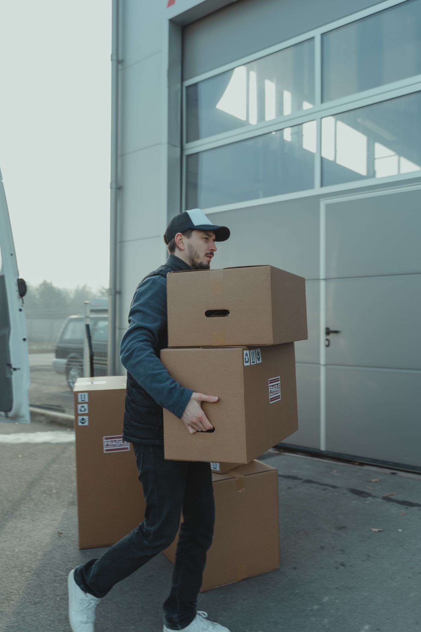 Logistics worker carrying cartons toward an industrial loading area
